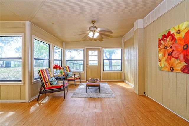 sunroom / solarium featuring wood finished floors, wooden walls, and plenty of natural light