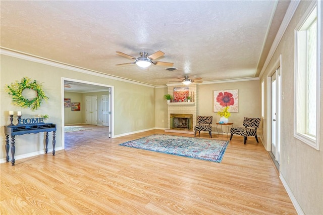 sitting room with wood finished floors, a ceiling fan, baseboards, a fireplace, and a textured ceiling