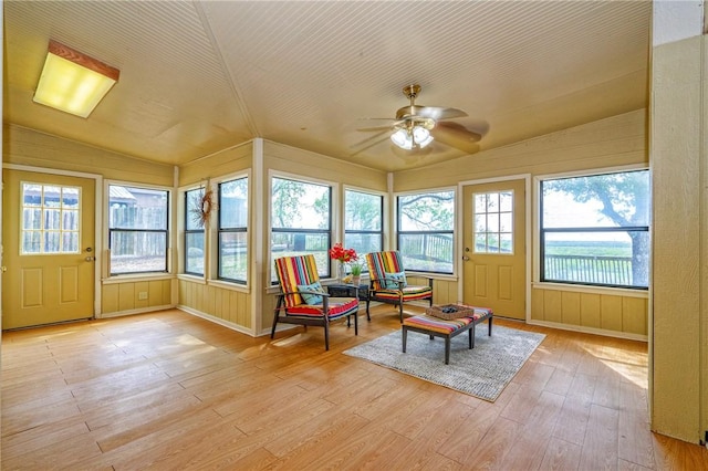 sunroom / solarium with vaulted ceiling, baseboards, and wood finished floors