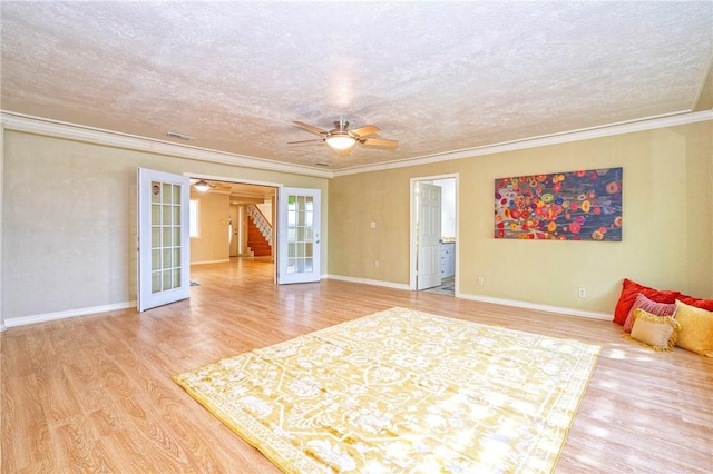 interior space featuring a ceiling fan, a textured ceiling, light wood-style floors, and ornamental molding