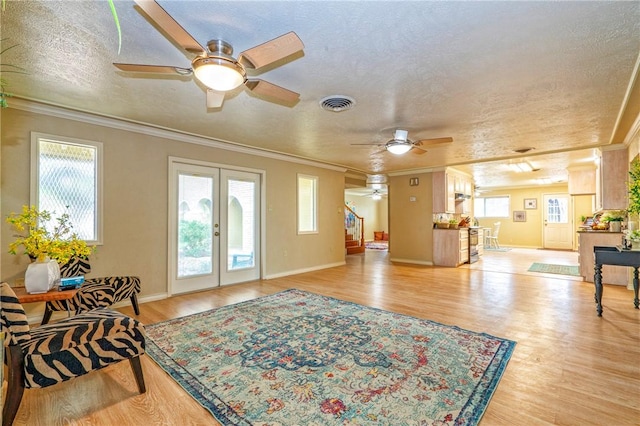 living room with a ceiling fan, visible vents, a wealth of natural light, and light wood-style flooring