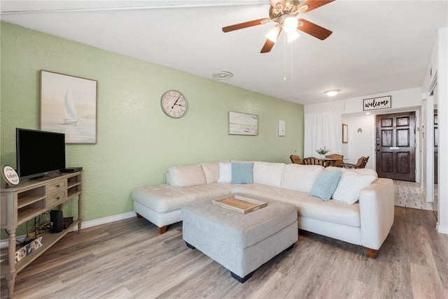 living room featuring wood finished floors, a ceiling fan, and baseboards