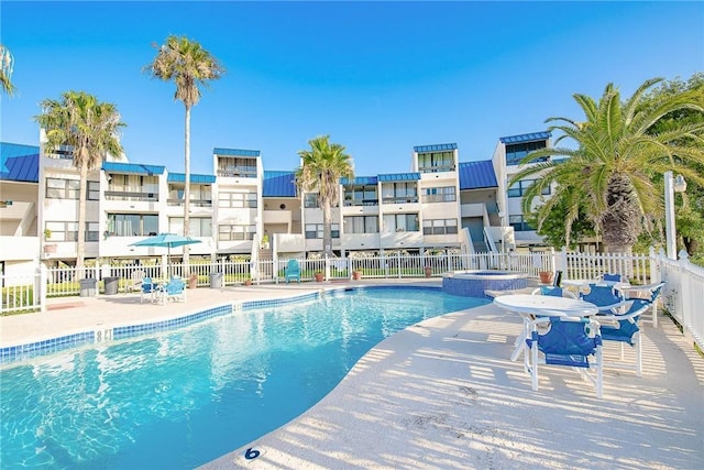 view of swimming pool with a pool with connected hot tub, a patio area, and fence