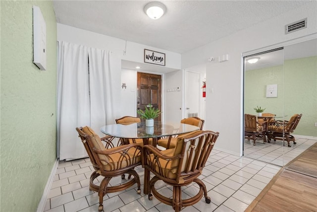 dining space featuring light tile patterned floors, visible vents, and baseboards