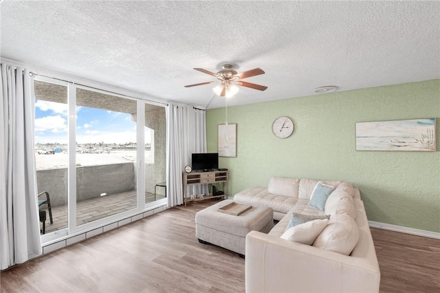 living area featuring ceiling fan, a textured ceiling, wood finished floors, and a textured wall