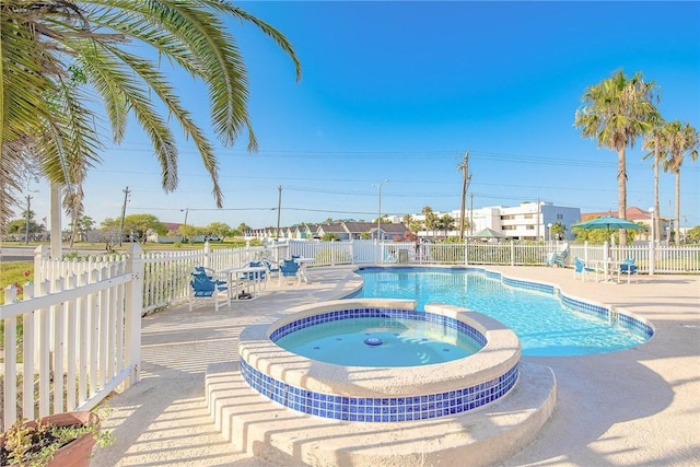 view of swimming pool with a pool with connected hot tub, a patio area, and fence