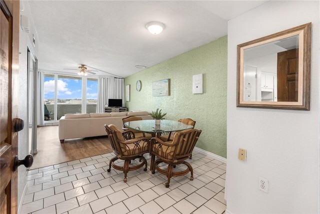 dining room featuring a textured wall, a ceiling fan, and baseboards