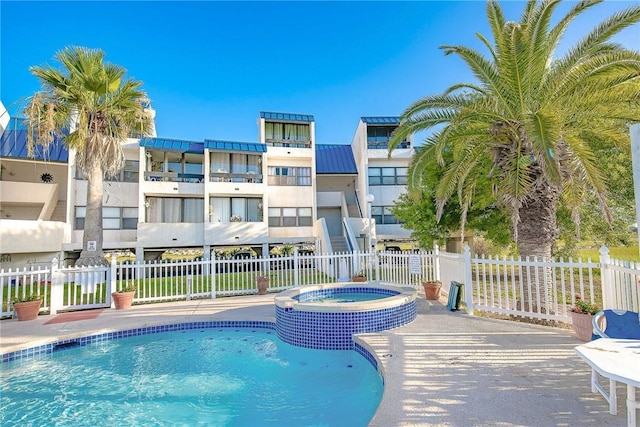 view of pool featuring a pool with connected hot tub and fence