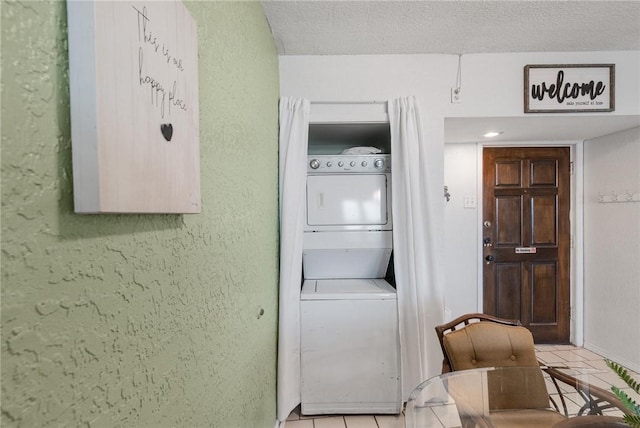 laundry room featuring stacked washer and dryer, laundry area, a textured wall, and light tile patterned floors