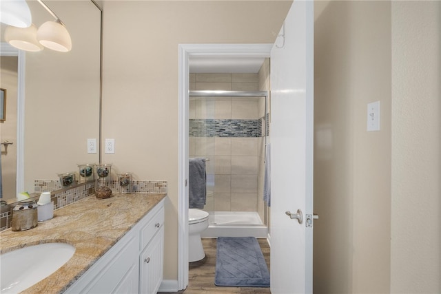 bathroom featuring wood-type flooring, vanity, toilet, and walk in shower