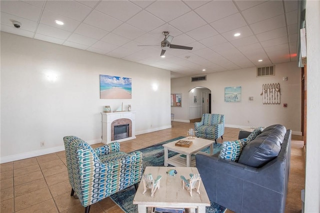 tiled living room featuring ceiling fan and a fireplace