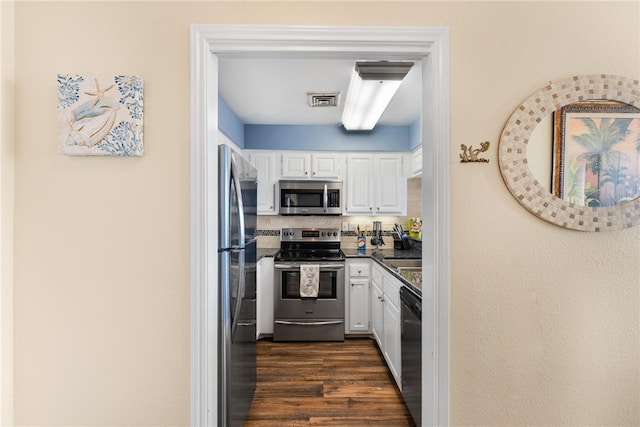 kitchen with white cabinets, dark hardwood / wood-style floors, backsplash, and appliances with stainless steel finishes