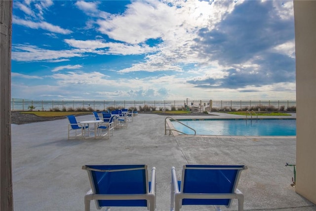 view of pool featuring a water view and a patio