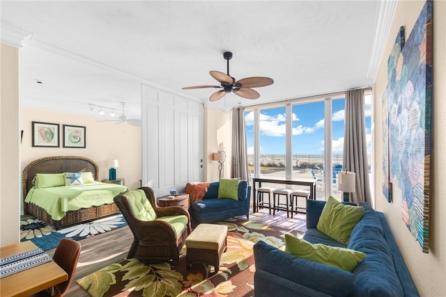 bedroom featuring ceiling fan, hardwood / wood-style floors, ornamental molding, and a wall of windows