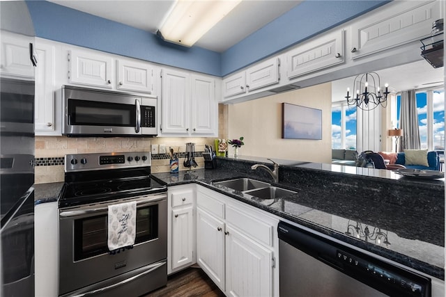 kitchen with sink, stainless steel appliances, tasteful backsplash, a chandelier, and white cabinets