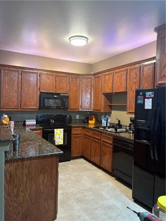 915 Flour Bluff Dr, Corpus Christi, TX 78418 - kitchen with black appliances, a sink, brown cabinetry, and dark stone countertops