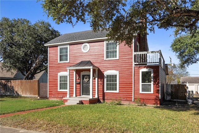 view of front of house featuring a balcony and a front lawn