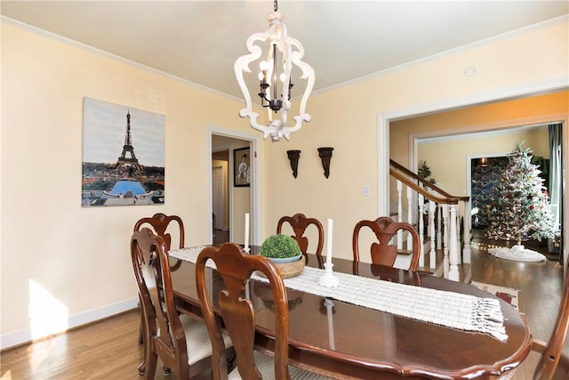 dining space with crown molding, wood-type flooring, and an inviting chandelier