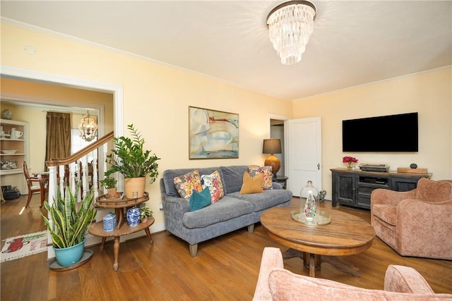 living room with crown molding, hardwood / wood-style floors, and an inviting chandelier