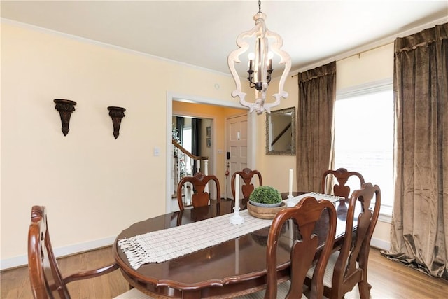 dining area with light hardwood / wood-style flooring, plenty of natural light, a notable chandelier, and crown molding