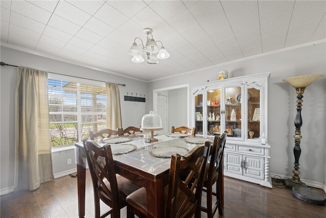 dining space featuring dark wood-type flooring, a notable chandelier, and ornamental molding