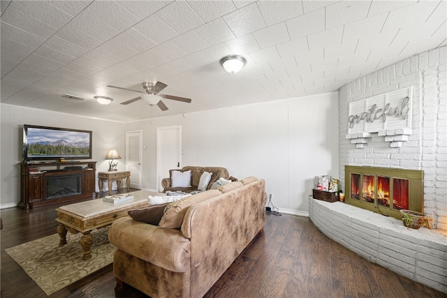 living room featuring a fireplace, dark wood-type flooring, and ceiling fan