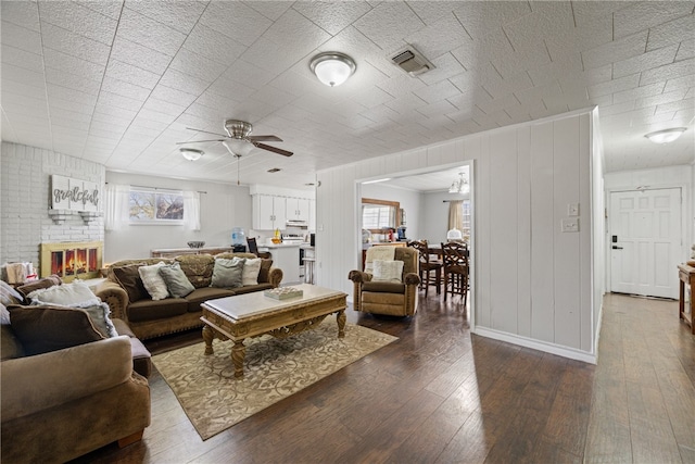 living room featuring a fireplace, dark wood-type flooring, a healthy amount of sunlight, and ceiling fan