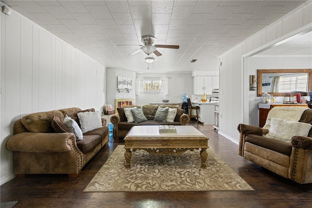 living room featuring wood walls, ceiling fan, and dark hardwood / wood-style floors