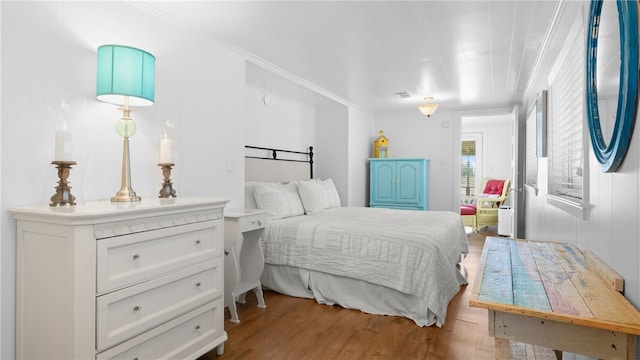 bedroom with crown molding and wood finished floors