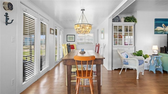 dining space with ornamental molding, wood finished floors, and a notable chandelier