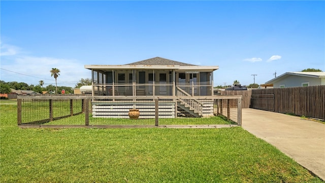 view of front of home with fence, a sunroom, concrete driveway, roof with shingles, and a front yard