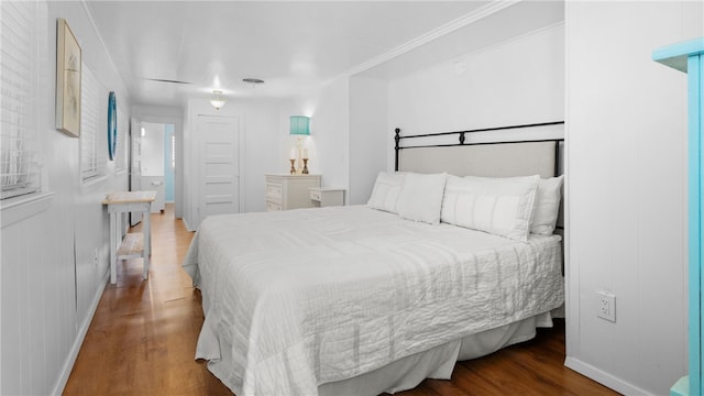 bedroom with baseboards, wood finished floors, and ornamental molding