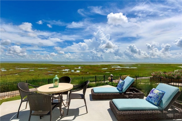 view of patio / terrace with outdoor dining area, a water view, and fence