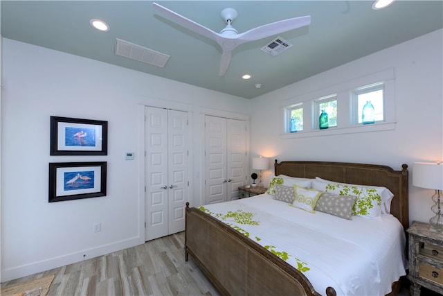 bedroom with multiple closets, light wood-type flooring, and ceiling fan