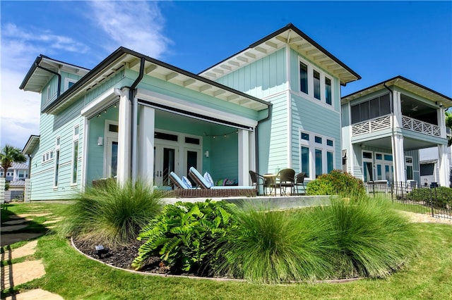 rear view of house featuring board and batten siding, french doors, a patio area, and fence