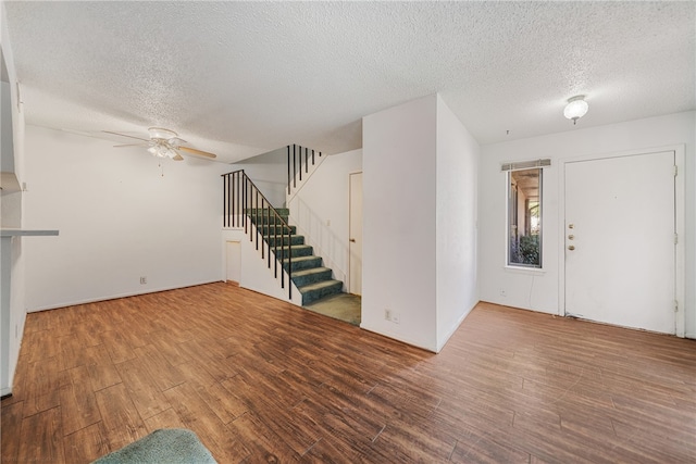 unfurnished living room with ceiling fan, wood-type flooring, and a textured ceiling