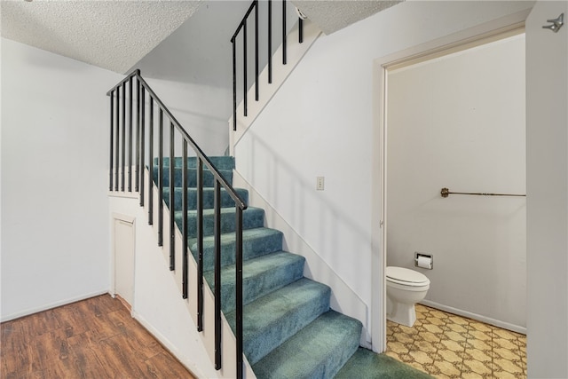 stairs featuring wood-type flooring and a textured ceiling