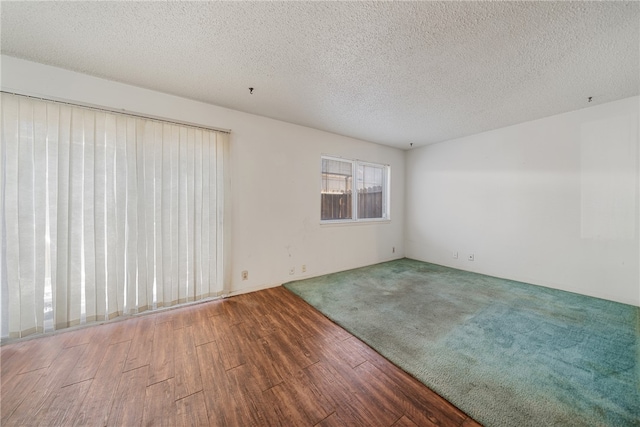 empty room featuring wood-type flooring and a textured ceiling