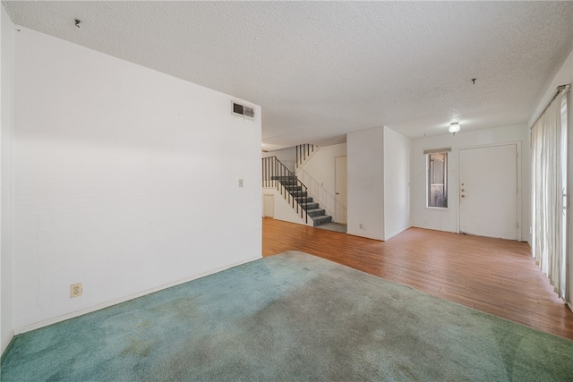 unfurnished living room featuring a textured ceiling and hardwood / wood-style flooring