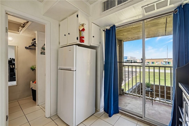 14300 S Padre Island Dr Unit 125, Corpus Christi, TX 78418 - kitchen with freestanding refrigerator, light tile patterned floors, and white cabinetry