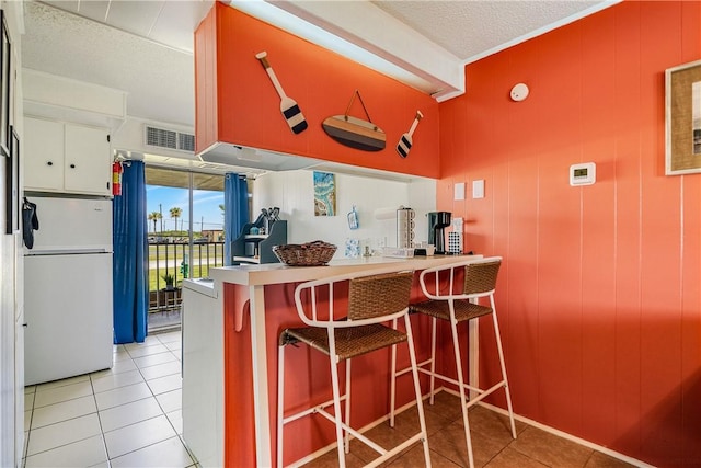 14300 S Padre Island Dr Unit 125, Corpus Christi, TX 78418 - kitchen featuring freestanding refrigerator, light tile patterned floors, a peninsula, and a kitchen breakfast bar