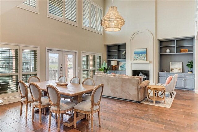 314 Bahia Mar Prt, Aransas, TX 78373 - dining area featuring a towering ceiling, french doors, light wood-style floors, built in features, and a notable chandelier