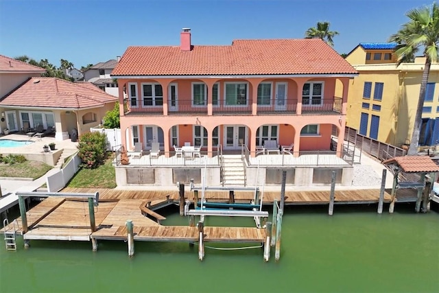314 Bahia Mar Prt, Aransas, TX 78373 - rear view of house featuring a tile roof, a water view, a chimney, a patio, and stucco siding