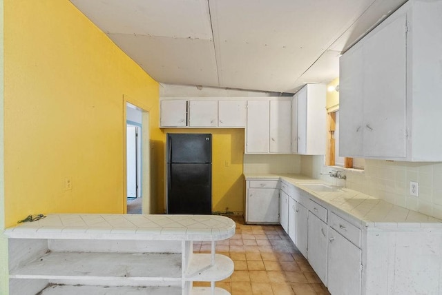925 Hazel Dr, Corpus Christi, TX 78412 - kitchen with freestanding refrigerator, tile countertops, white cabinets, and tasteful backsplash