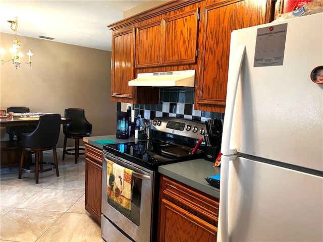 kitchen with backsplash, extractor fan, white refrigerator, a notable chandelier, and stainless steel electric range oven