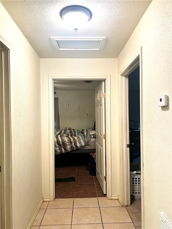 hallway featuring a textured ceiling and light tile patterned floors