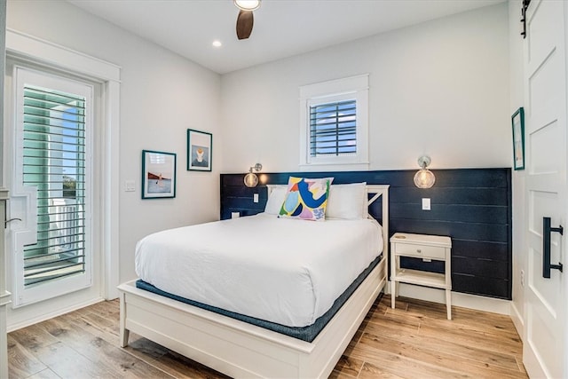 bedroom with recessed lighting, access to outside, light wood-style flooring, and a barn door