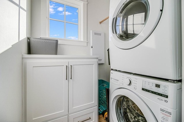 clothes washing area with cabinet space and stacked washing maching and dryer