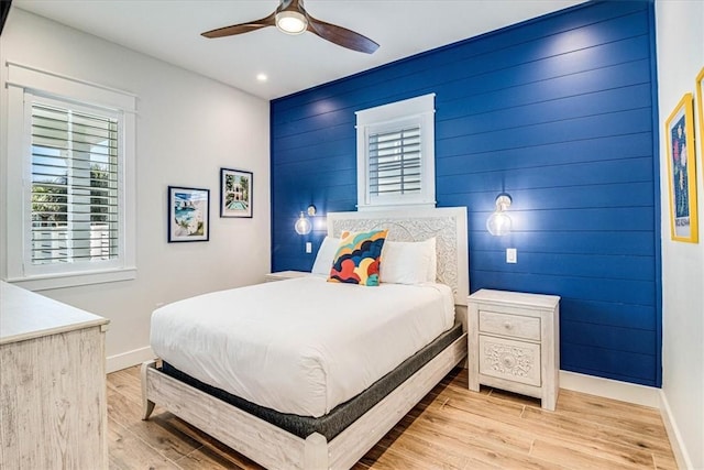 bedroom featuring ceiling fan, light wood-style flooring, recessed lighting, an accent wall, and baseboards