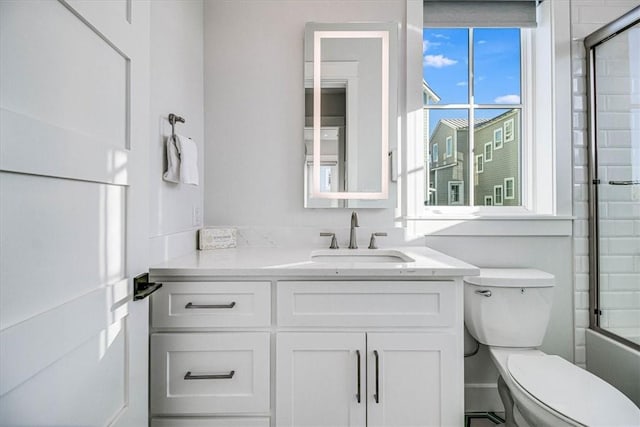 full bathroom with combined bath / shower with glass door, vanity, and toilet